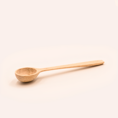 Ein praktischer Holz-Dosierlöffel 15 cm von FAVLY Petfood, aus Buchenholz mit einer flachen, runden Laffe auf hellrosa Hintergrund.