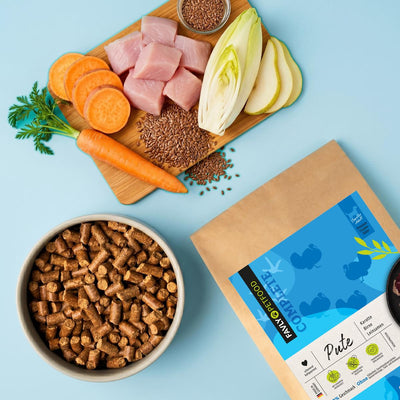 FAVLY Petfood Huhn mit Karotte, Birne & Leinsamen (gebacken) in Schale mit Gemüse, neben getreidefreiem Beutel.