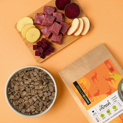 FAVLY Petfood Hirsch mit Kartoffel, Rote Bete & Apfel, serviert mit rohem Fleisch, Rote-Bete-Stückchen und Apfelscheiben.