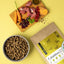 Hundefressnapf, rohes Gemüse und FAVLY Petfood Weidelamm mit Rote Beete Beutel auf einem leuchtend gelben Hintergrund.